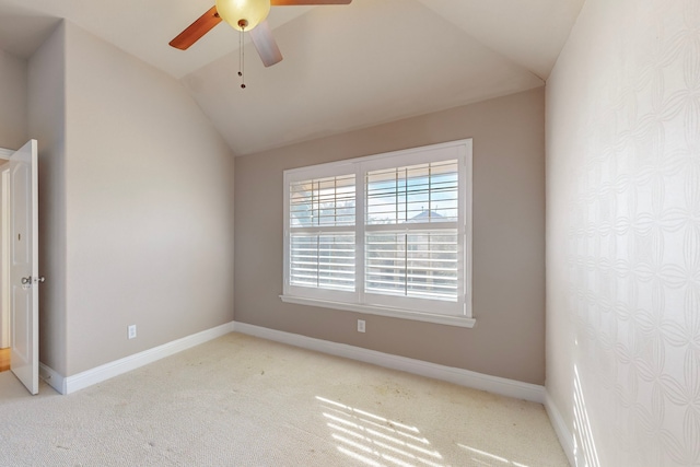 empty room featuring lofted ceiling, baseboards, and light colored carpet