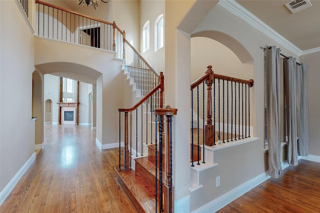 interior space with hardwood / wood-style flooring, ornamental molding, a high ceiling, and an inviting chandelier