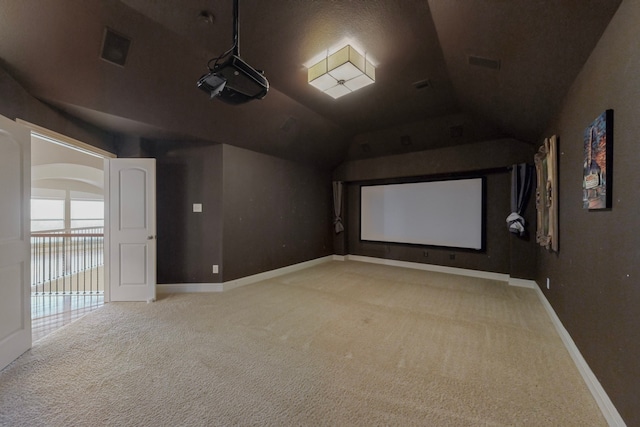 cinema room with light carpet, visible vents, baseboards, and vaulted ceiling