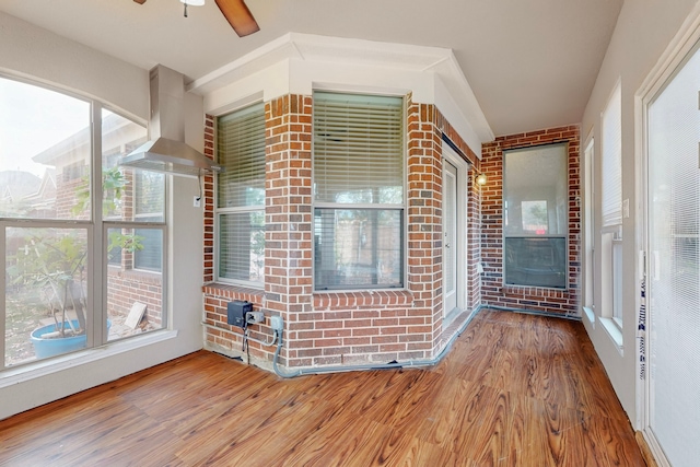 unfurnished sunroom with a ceiling fan and a fireplace