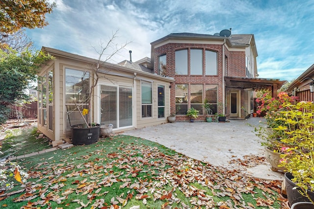 rear view of property featuring a patio area, fence, and brick siding