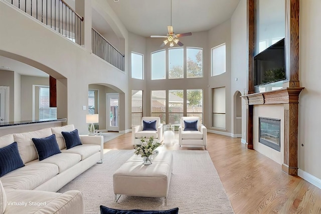 living room featuring light wood-style floors, a glass covered fireplace, and baseboards