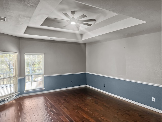 unfurnished room featuring ceiling fan, a raised ceiling, hardwood / wood-style floors, and a textured ceiling