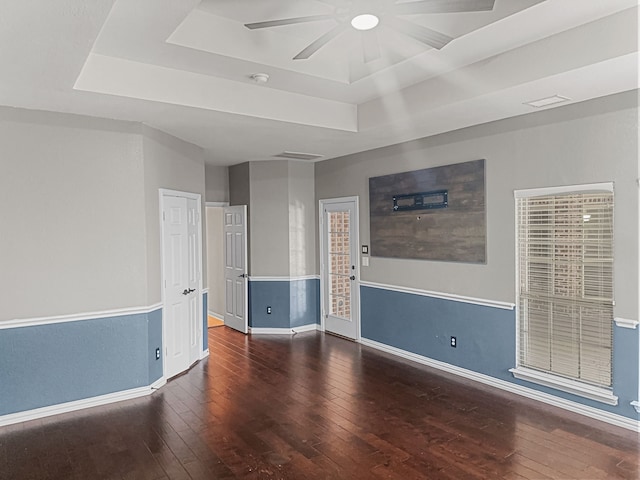 unfurnished room featuring ceiling fan, dark hardwood / wood-style floors, and a raised ceiling