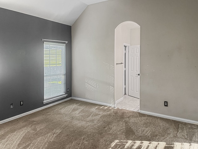 spare room featuring lofted ceiling and light carpet