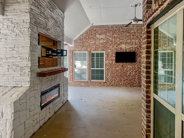 unfurnished living room with brick wall, lofted ceiling, concrete floors, and ceiling fan