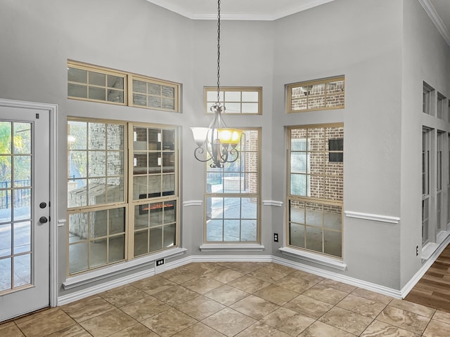 unfurnished dining area with a high ceiling, ornamental molding, tile patterned flooring, and a notable chandelier