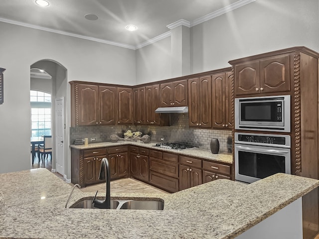 kitchen featuring ornamental molding, stainless steel appliances, sink, and dark brown cabinets