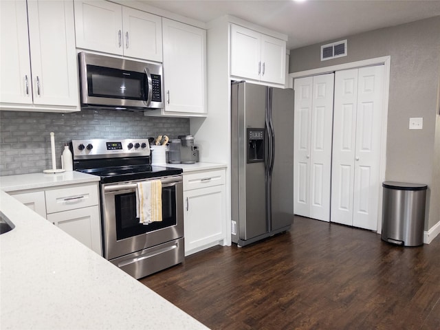 kitchen with dark hardwood / wood-style floors, decorative backsplash, white cabinetry, and stainless steel appliances