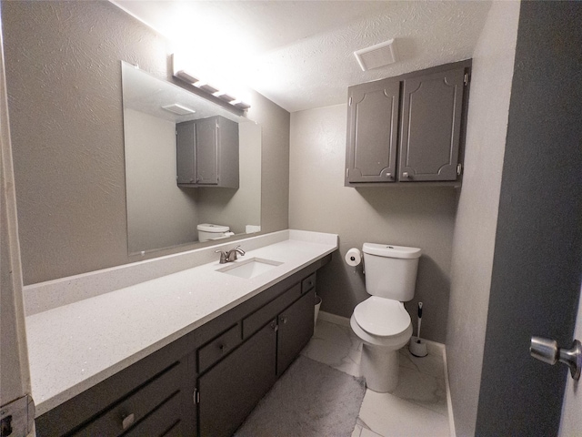 bathroom featuring vanity, toilet, and a textured ceiling