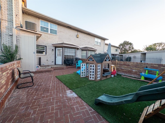 rear view of property with a playground and a patio area