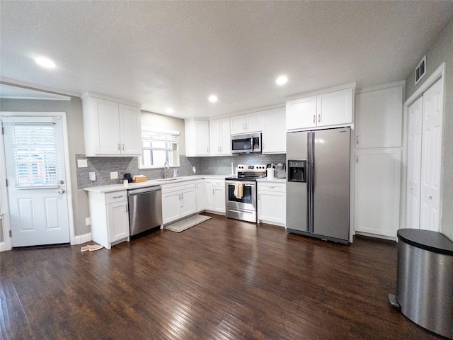 kitchen with backsplash, a textured ceiling, appliances with stainless steel finishes, dark hardwood / wood-style flooring, and white cabinetry