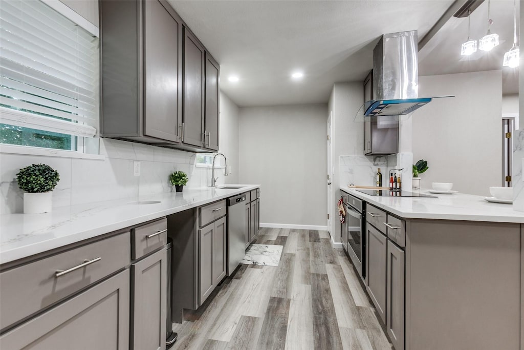 kitchen with pendant lighting, ventilation hood, sink, appliances with stainless steel finishes, and tasteful backsplash