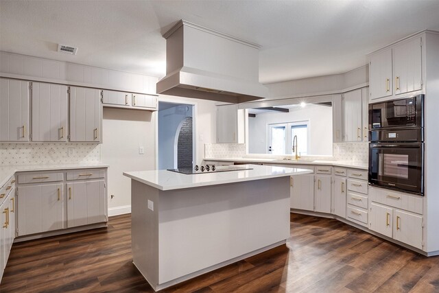 kitchen featuring dark hardwood / wood-style flooring, a kitchen island, black appliances, and sink