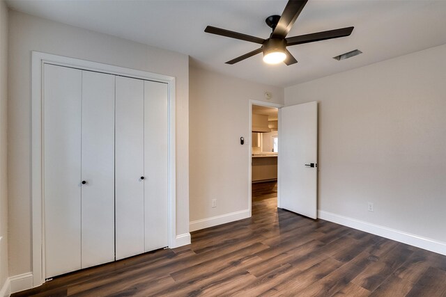 unfurnished bedroom with dark hardwood / wood-style flooring, a closet, and ceiling fan