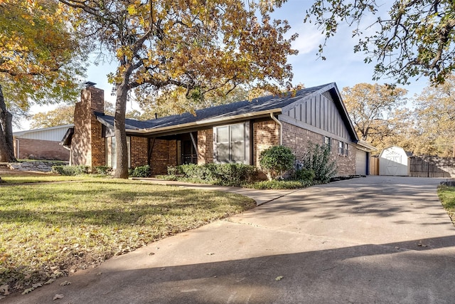 ranch-style house with a storage unit and a front lawn