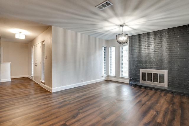 interior space featuring a fireplace, dark hardwood / wood-style floors, an inviting chandelier, and brick wall