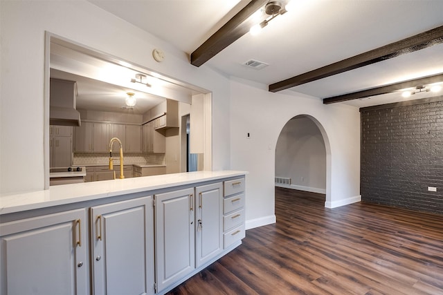 bathroom featuring beamed ceiling, wood-type flooring, tasteful backsplash, and brick wall