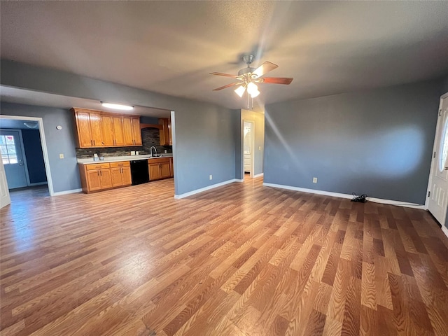 unfurnished living room with ceiling fan, sink, and light wood-type flooring