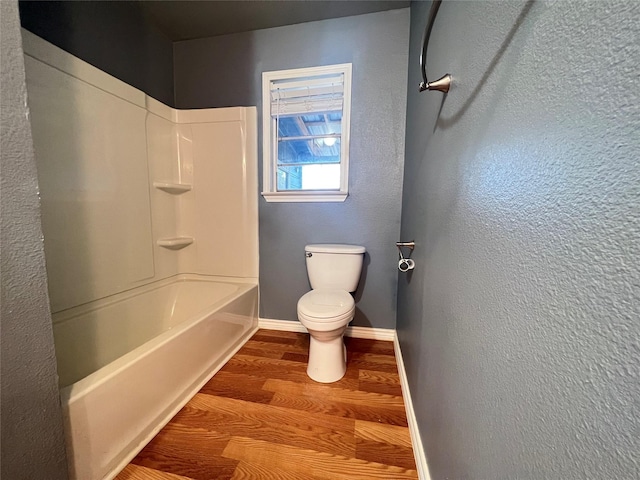 bathroom featuring hardwood / wood-style flooring, bathing tub / shower combination, and toilet