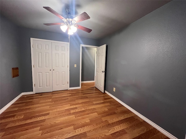 unfurnished bedroom featuring hardwood / wood-style floors, a closet, and ceiling fan