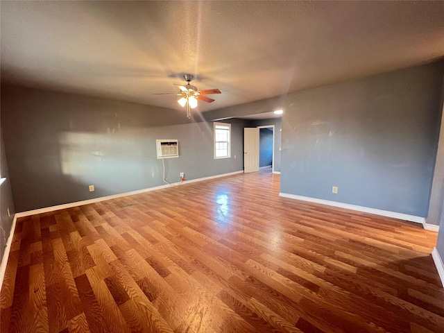 spare room with ceiling fan, hardwood / wood-style floors, a textured ceiling, and a wall unit AC