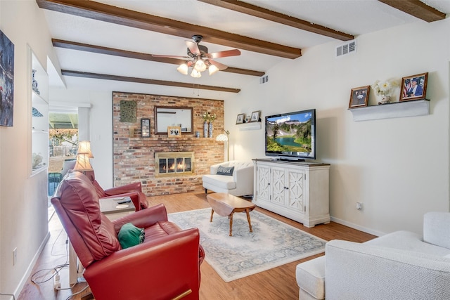 living room with beam ceiling, ceiling fan, light hardwood / wood-style flooring, and a brick fireplace