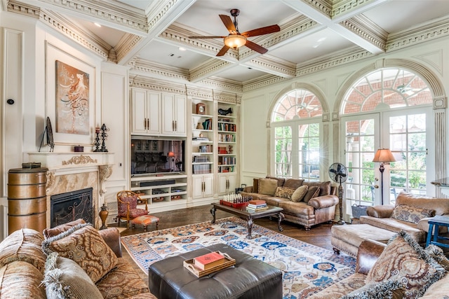 living room with coffered ceiling, built in shelves, a premium fireplace, and hardwood / wood-style flooring