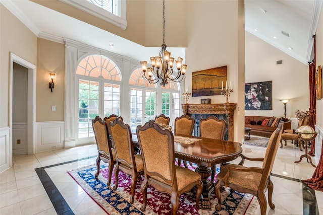 dining space featuring an inviting chandelier, a towering ceiling, a wealth of natural light, and ornamental molding