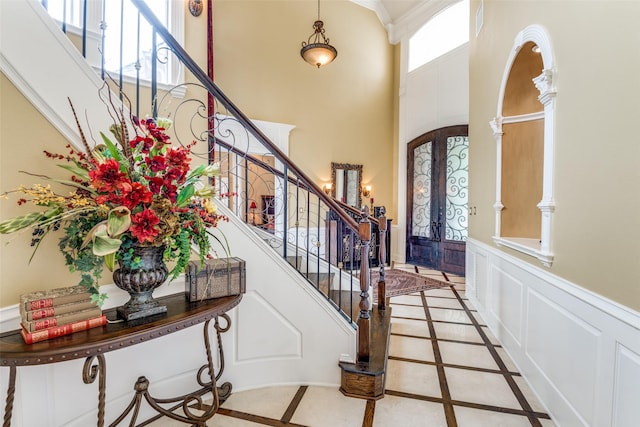 entrance foyer with french doors, ornate columns, and a high ceiling