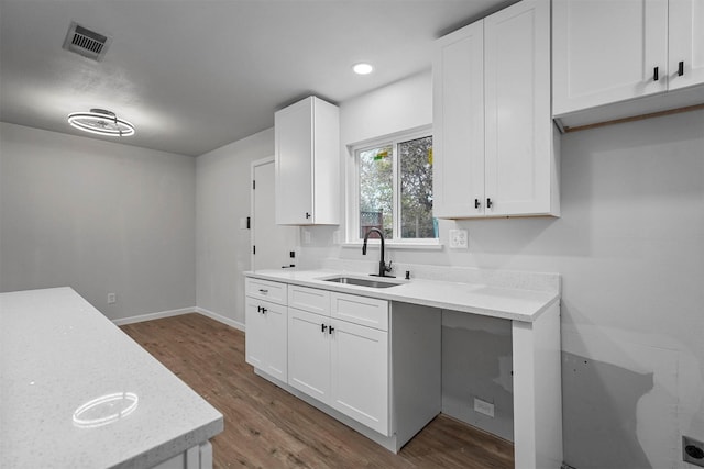 kitchen with sink, white cabinets, and wood-type flooring