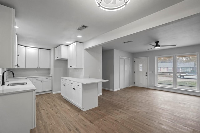 kitchen with ceiling fan, sink, white cabinets, and light hardwood / wood-style flooring