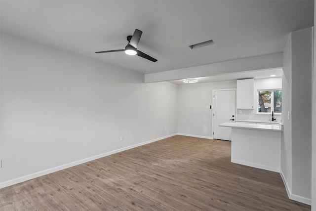 unfurnished living room featuring hardwood / wood-style floors, ceiling fan, and sink