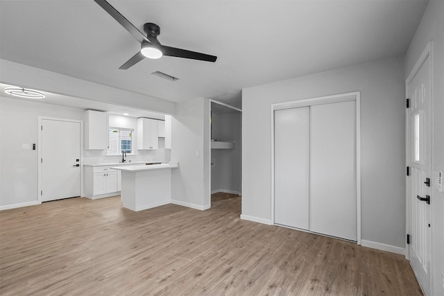 unfurnished living room featuring ceiling fan, light hardwood / wood-style floors, and sink