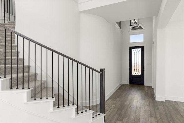 foyer featuring dark hardwood / wood-style flooring, a towering ceiling, and an inviting chandelier