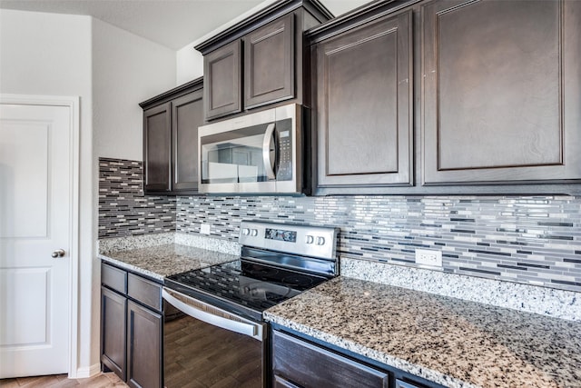 kitchen with appliances with stainless steel finishes, light hardwood / wood-style flooring, dark brown cabinets, and light stone counters