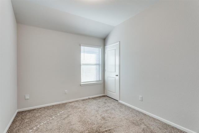 unfurnished room featuring light colored carpet and vaulted ceiling