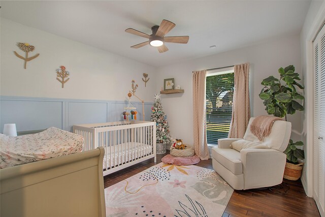 bedroom with dark hardwood / wood-style flooring, a crib, a closet, and ceiling fan