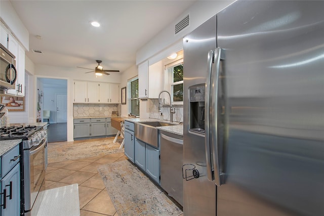 kitchen featuring light tile patterned floors, stainless steel appliances, white cabinets, blue cabinets, and decorative backsplash