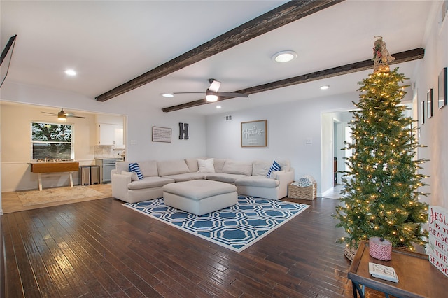 living room featuring dark hardwood / wood-style flooring, beam ceiling, and ceiling fan