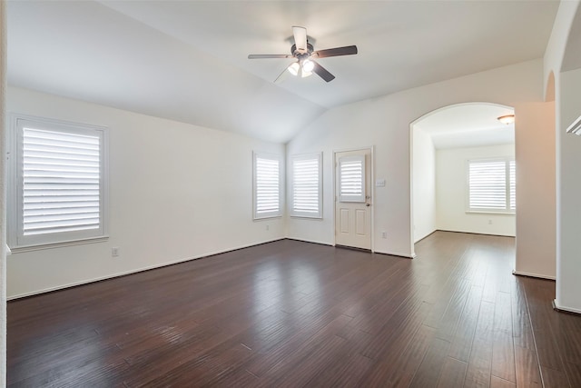 empty room featuring ceiling fan, plenty of natural light, vaulted ceiling, and dark wood finished floors