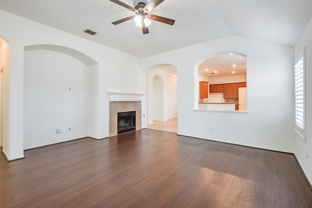 unfurnished living room with ceiling fan, a fireplace, wood finished floors, visible vents, and vaulted ceiling