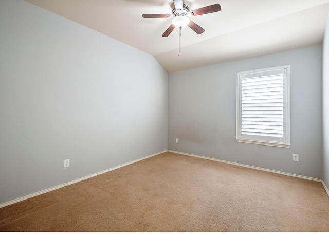 carpeted spare room featuring baseboards, vaulted ceiling, and a ceiling fan