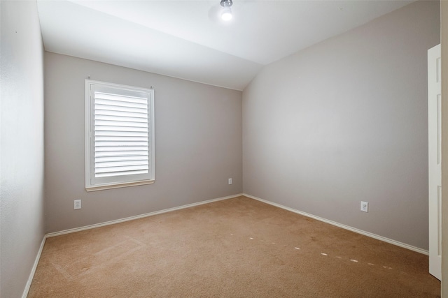 unfurnished room featuring baseboards, vaulted ceiling, and light colored carpet