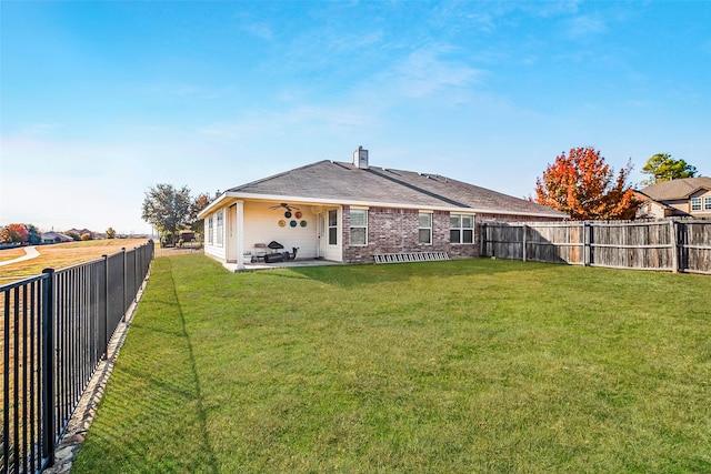 rear view of house featuring a yard, a patio area, and a fenced backyard