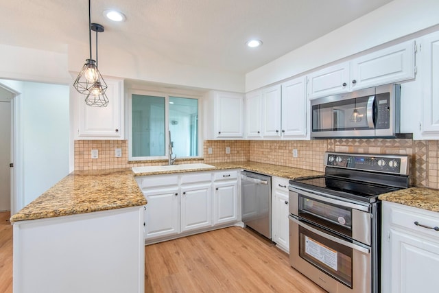 kitchen featuring decorative light fixtures, sink, white cabinets, light hardwood / wood-style floors, and stainless steel appliances