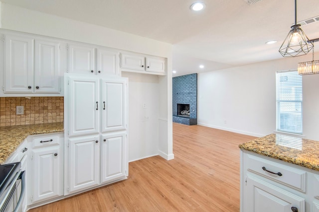 kitchen featuring white cabinetry, decorative light fixtures, light stone counters, and stainless steel electric range