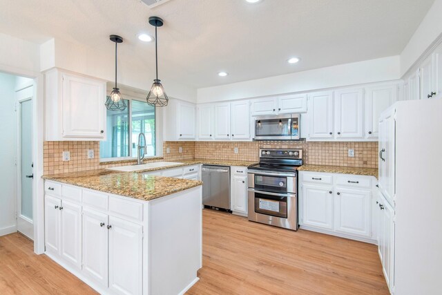 kitchen featuring hanging light fixtures, white cabinetry, appliances with stainless steel finishes, and kitchen peninsula