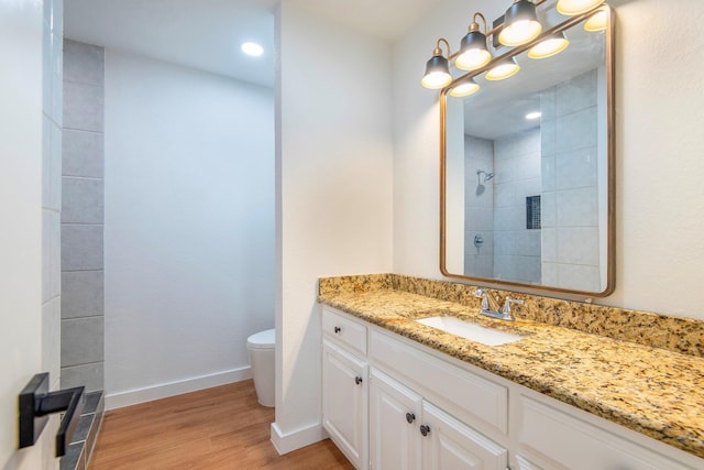 bathroom featuring hardwood / wood-style flooring, vanity, toilet, and a shower