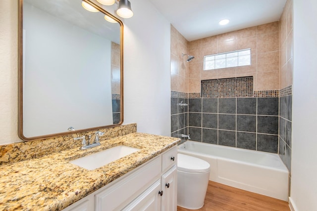 full bathroom featuring tiled shower / bath, vanity, toilet, and hardwood / wood-style floors